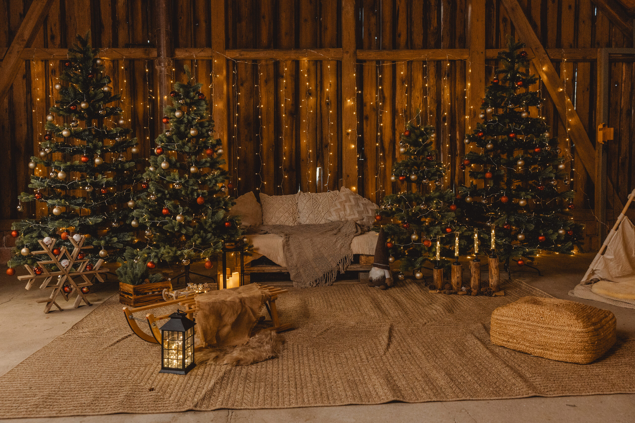 Gemütliche Weihnachtskulisse mit Sofa, Holzschlitten und leuchtenden Tannenbäumen