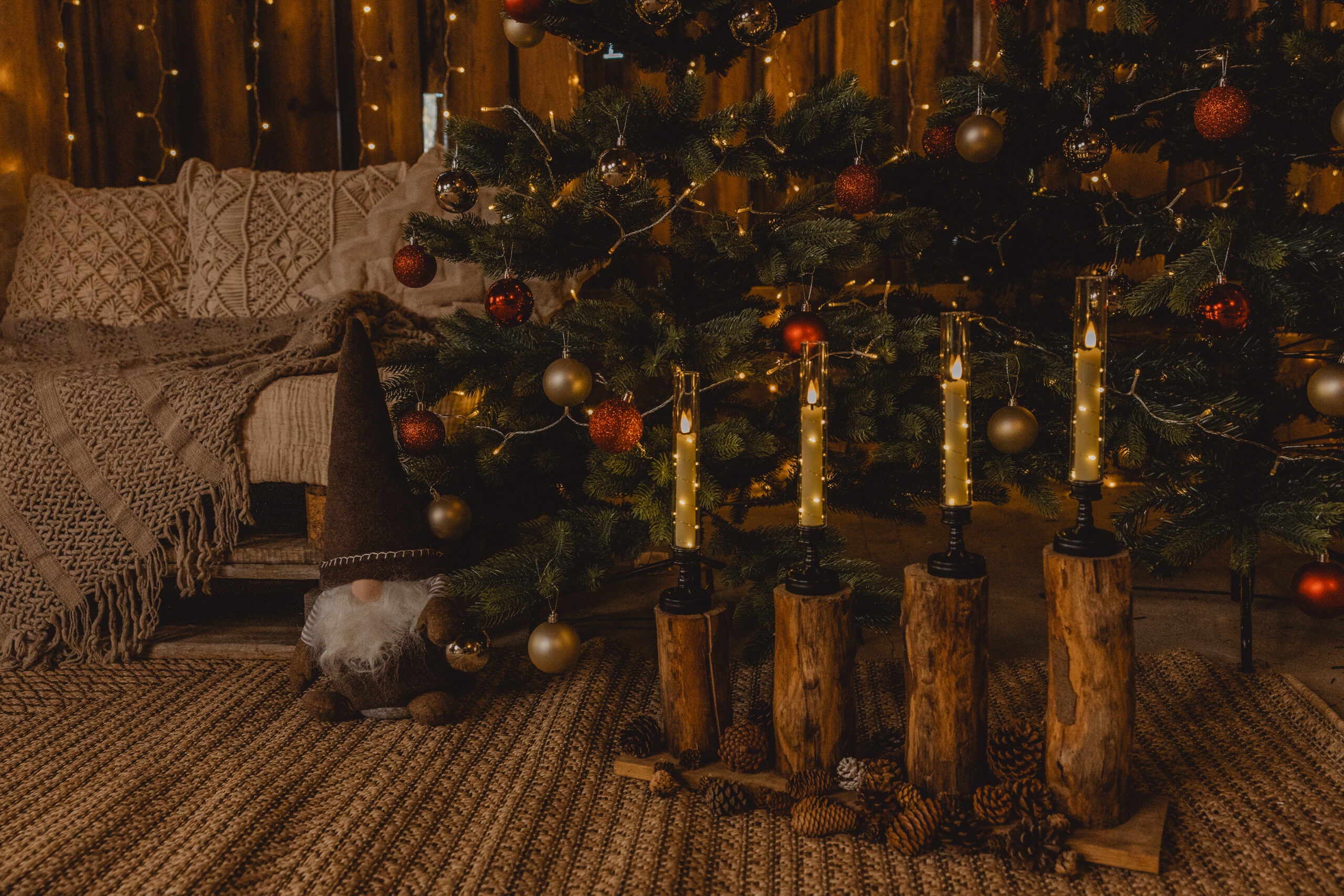 Weihnachtsbaum mit Kugeln und Kerzen auf rustikalen Holzständern